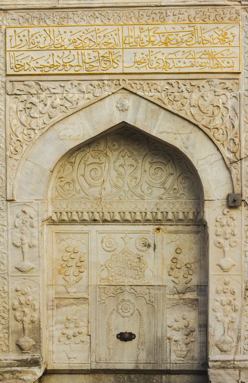 Free Ornate stone archway adorned with Arabic calligraphy and floral motifs. Stock Photo
