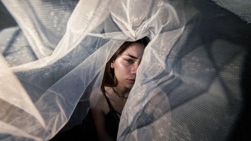 Free Portrait of a woman expressing introspection amidst ethereal flowing fabrics in Çanakkale, Türkiye. Stock Photo