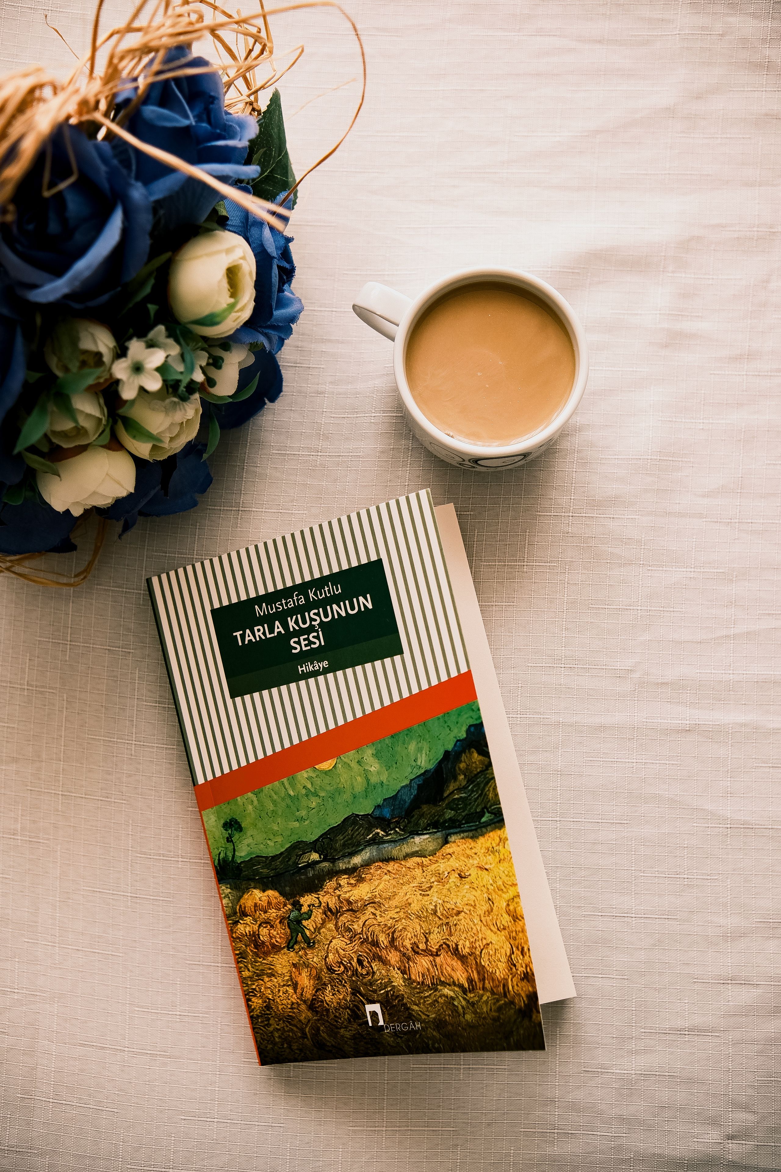 Book, coffee, and flowers on a table create a cozy reading scene.