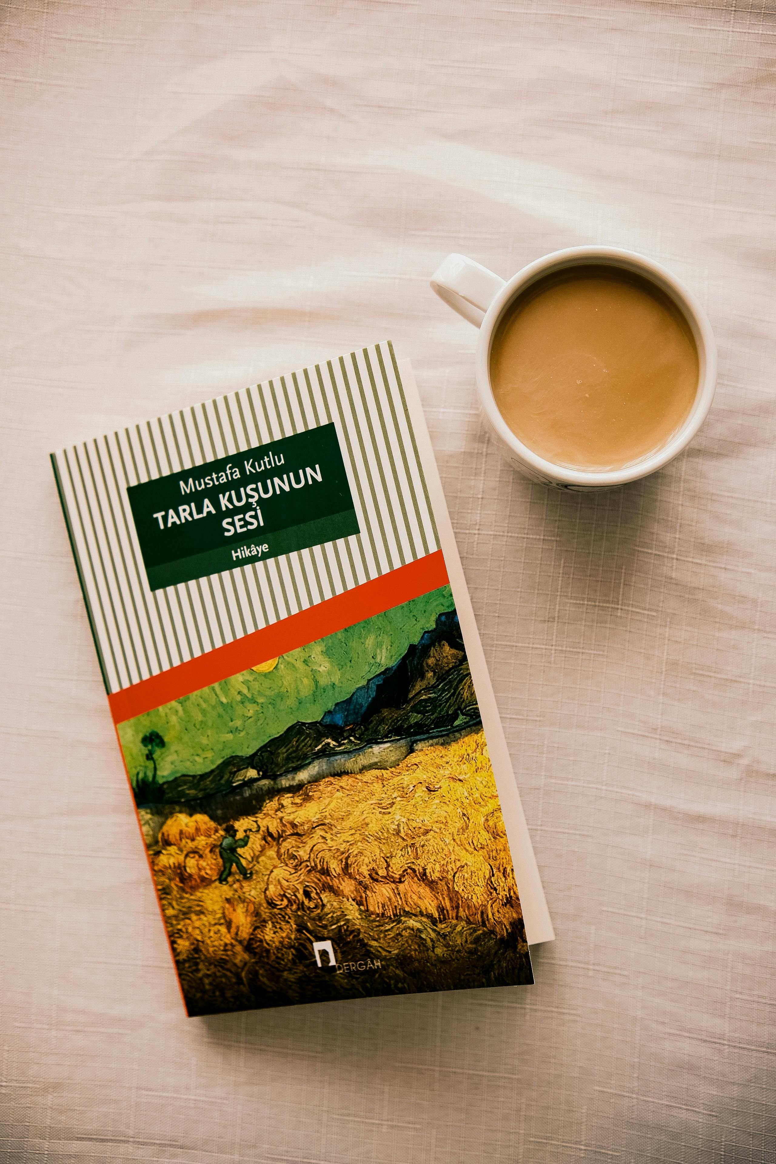 A book with coffee on a textured white tablecloth creates a cozy reading vibe.
