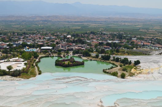 Vista panoramica delle terrazze di travertino di Pamukkale e del villaggio vicino sotto un cielo limpido.