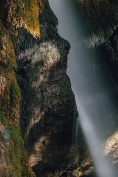 A tranquil waterfall cascades over mossy rocks in Sonthofen, Germany, capturing nature's beauty.