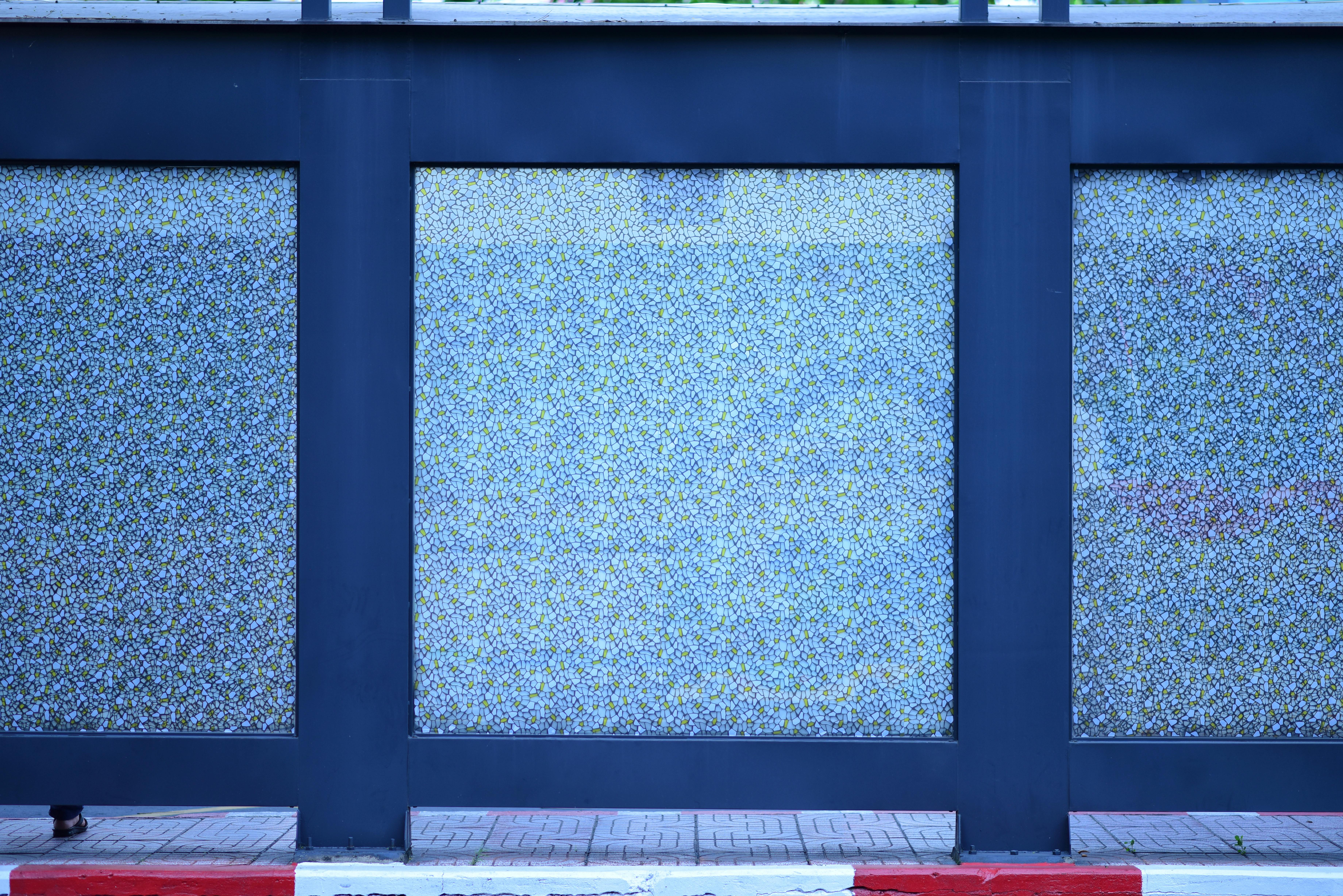 Gratis Abstrakt visning af en moderne væg med blå, blomstermønstrede glaspaneler og et dristigt geometrisk design. Lagerfoto