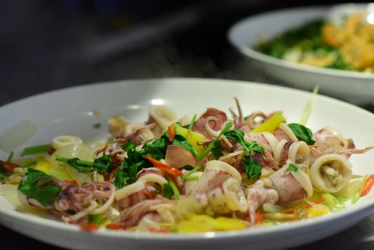 Close-up of a seafood salad featuring fresh squid, garnished with colorful vegetables.
