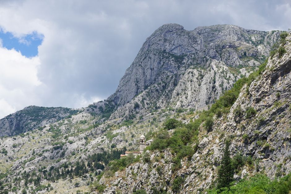 Traveler wearing modest attire with a scarf, visiting Ostrog Monastery in Montenegro.