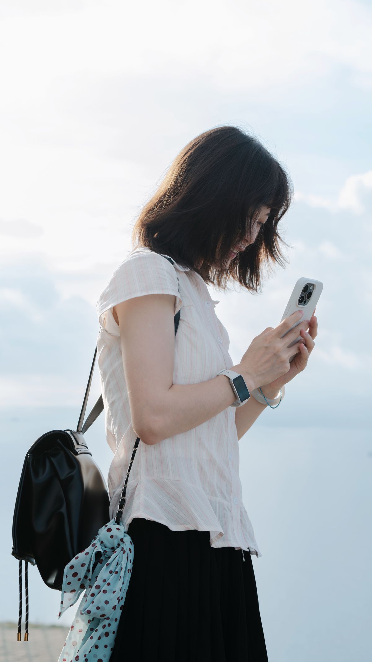 屋外でスマートフォンを操作する女性