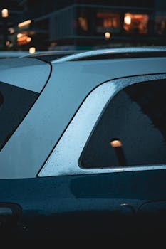 Artistic view of a car window with raindrops, capturing a moody twilight city scene.