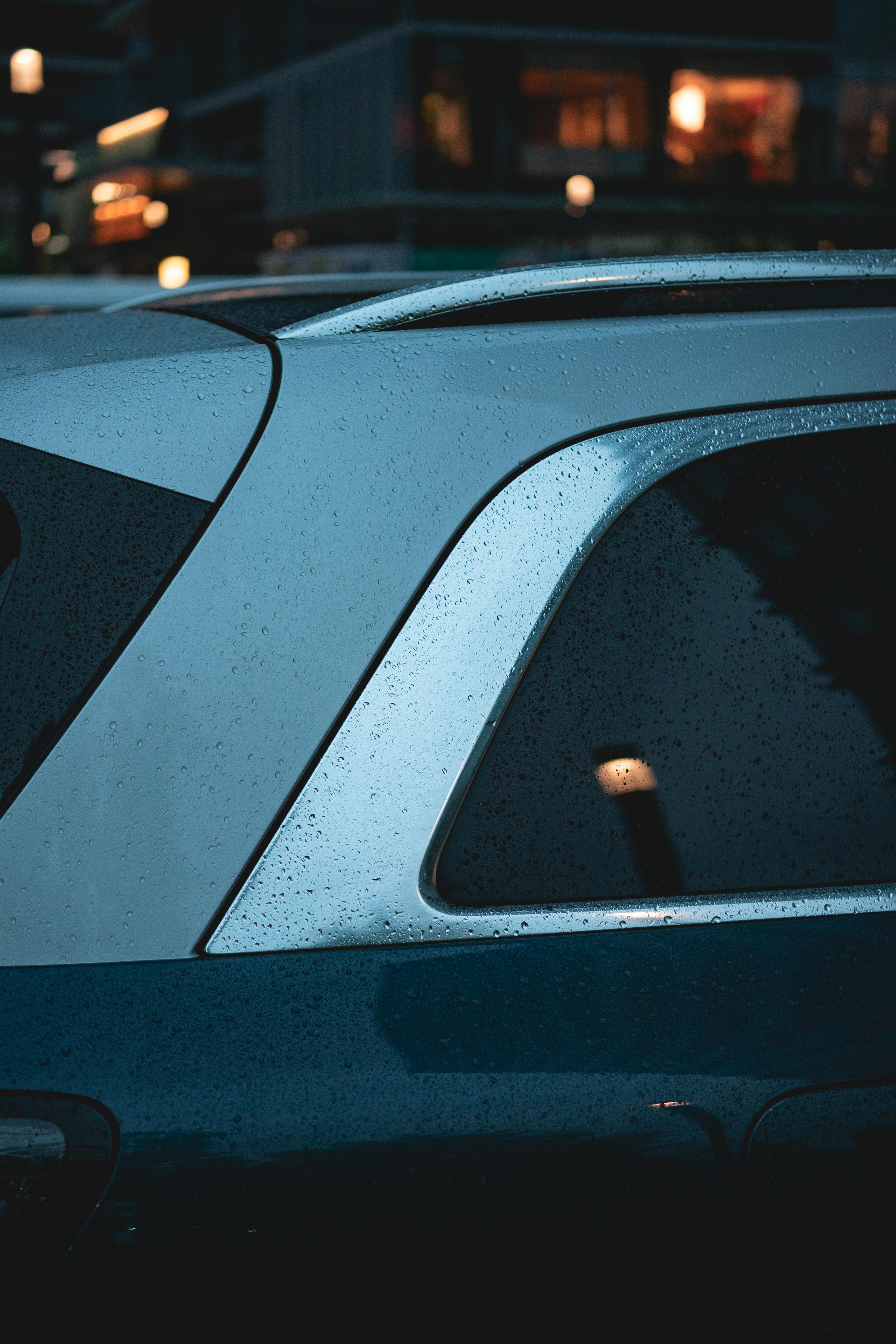 Free Artistic view of a car window with raindrops, capturing a moody twilight city scene. Stock Photo