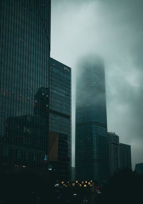 Free Dramatic cityscape featuring modern skyscrapers shrouded in fog, creating a mysterious urban skyline. Stock Photo