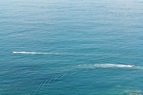 Free Aerial shot of boats creating trails on tranquil blue ocean waters. Stock Photo
