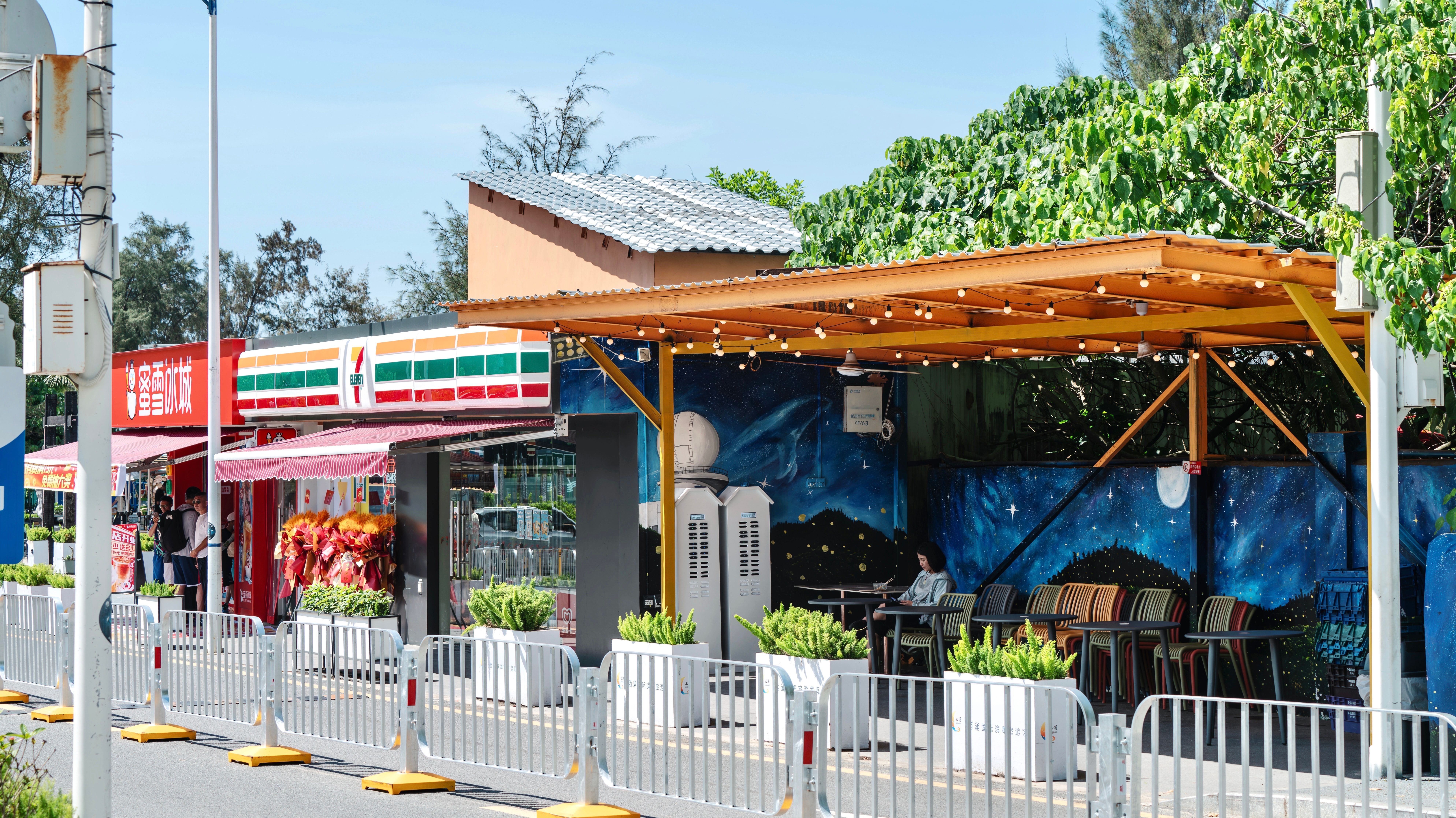 Bright outdoor café with a vibrant mural next to popular shops.