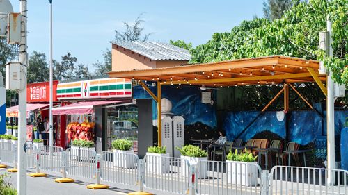 Free Bright outdoor café with a vibrant mural next to popular shops. Stock Photo