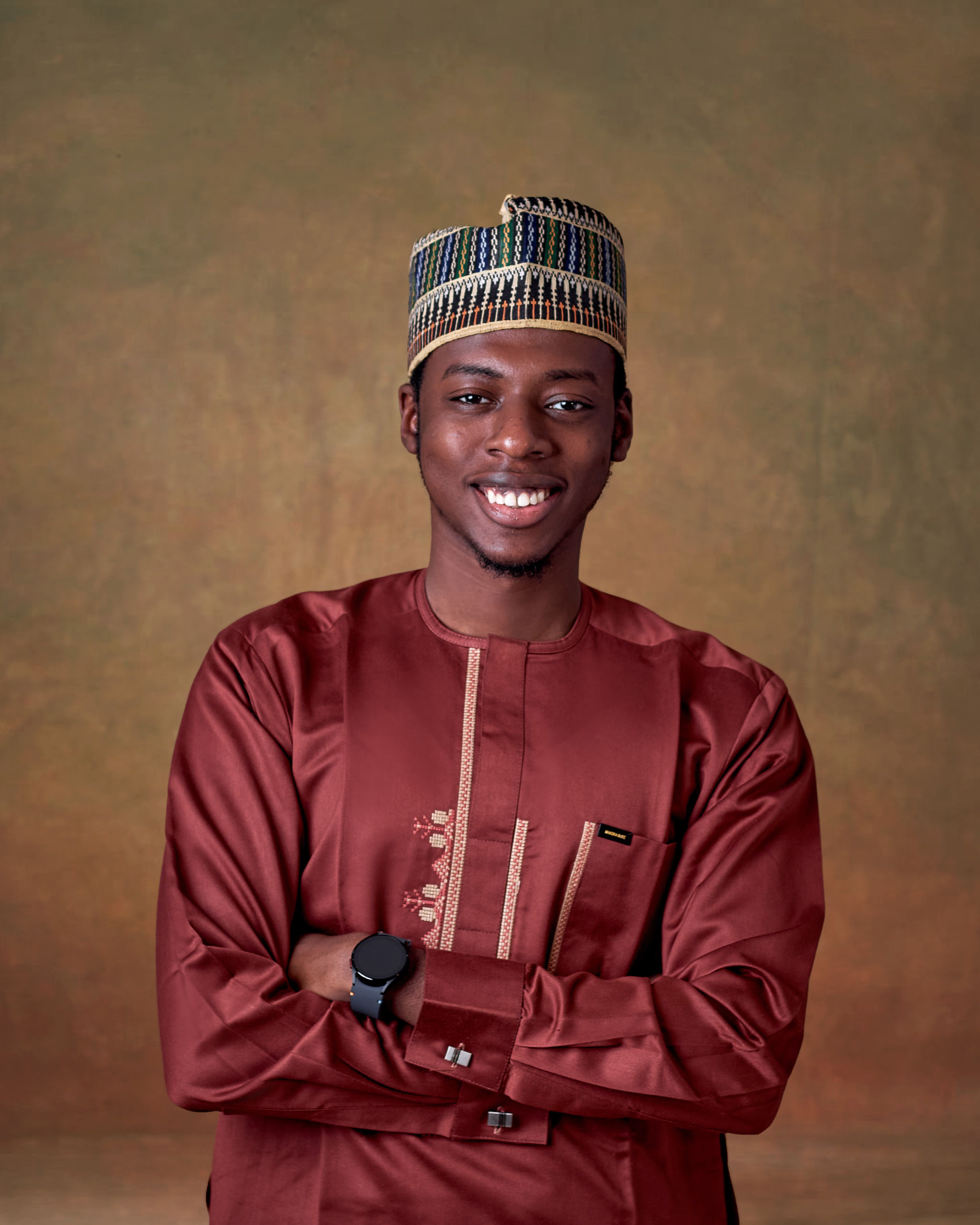 Smiling man in traditional African attire with a watch against a textured background.