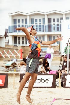 Dynamic shot of a beach volleyball player mid-air during a game in England.