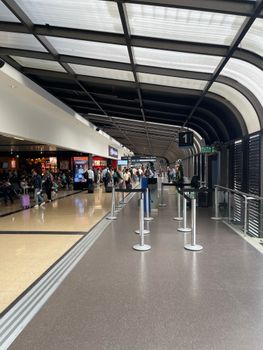 A busy airport terminal featuring shops and travelers waiting and walking.