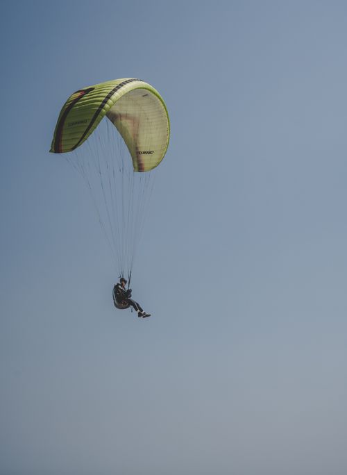 Free A paraglider soaring in the clear blue sky, highlighting the thrill of adventure sports. Stock Photo