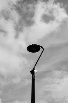 Black and white photo of a minimalist street light against cloudy sky in Bergamo, Italy.