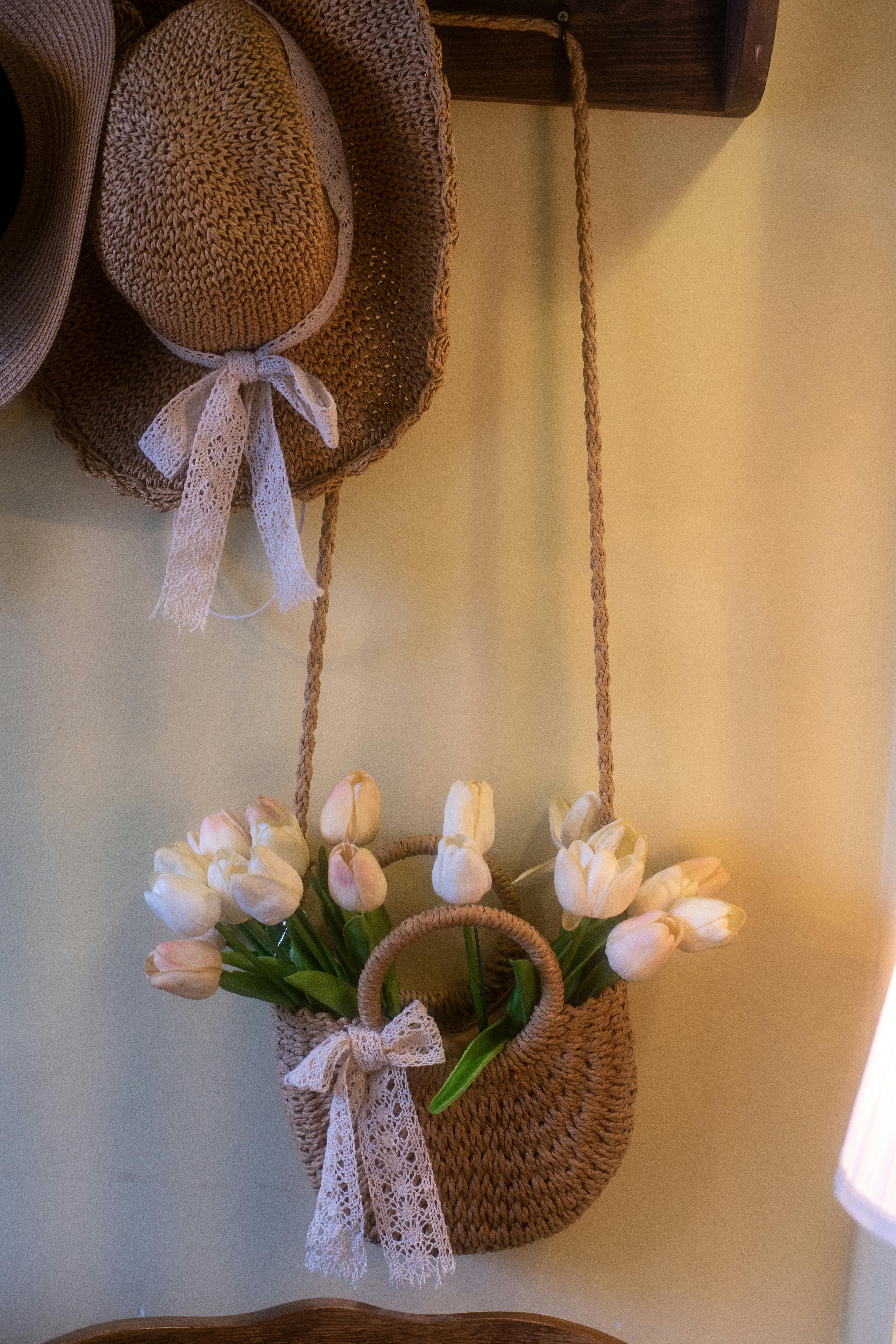 бесплатная Очаровательная сцена с соломенной шляпой и сумкой, полной тюльпанов, олицетворяющая деревенскую элегантность. Стоковое фото