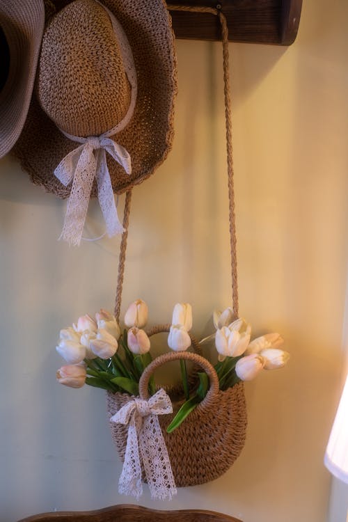 бесплатная Очаровательная сцена с соломенной шляпой и сумкой, полной тюльпанов, олицетворяющая деревенскую элегантность. Стоковое фото