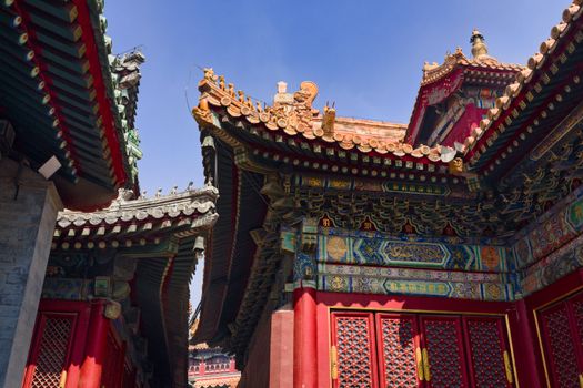 Intricate rooftop details of historical Chinese architecture under a blue sky in Beijing.