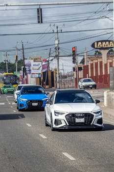 Luxury cars cruising along a busy street in Jamaica, capturing urban lifestyle.
