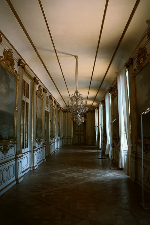 Free Luxurious palace hallway with decorative chandeliers and ornate wall details. Stock Photo