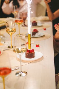 Elegant table setting with desserts and a sparkling candle at a celebration.