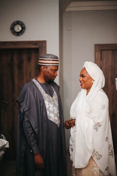 Elegant African couple in traditional attire during indoor wedding ceremony.