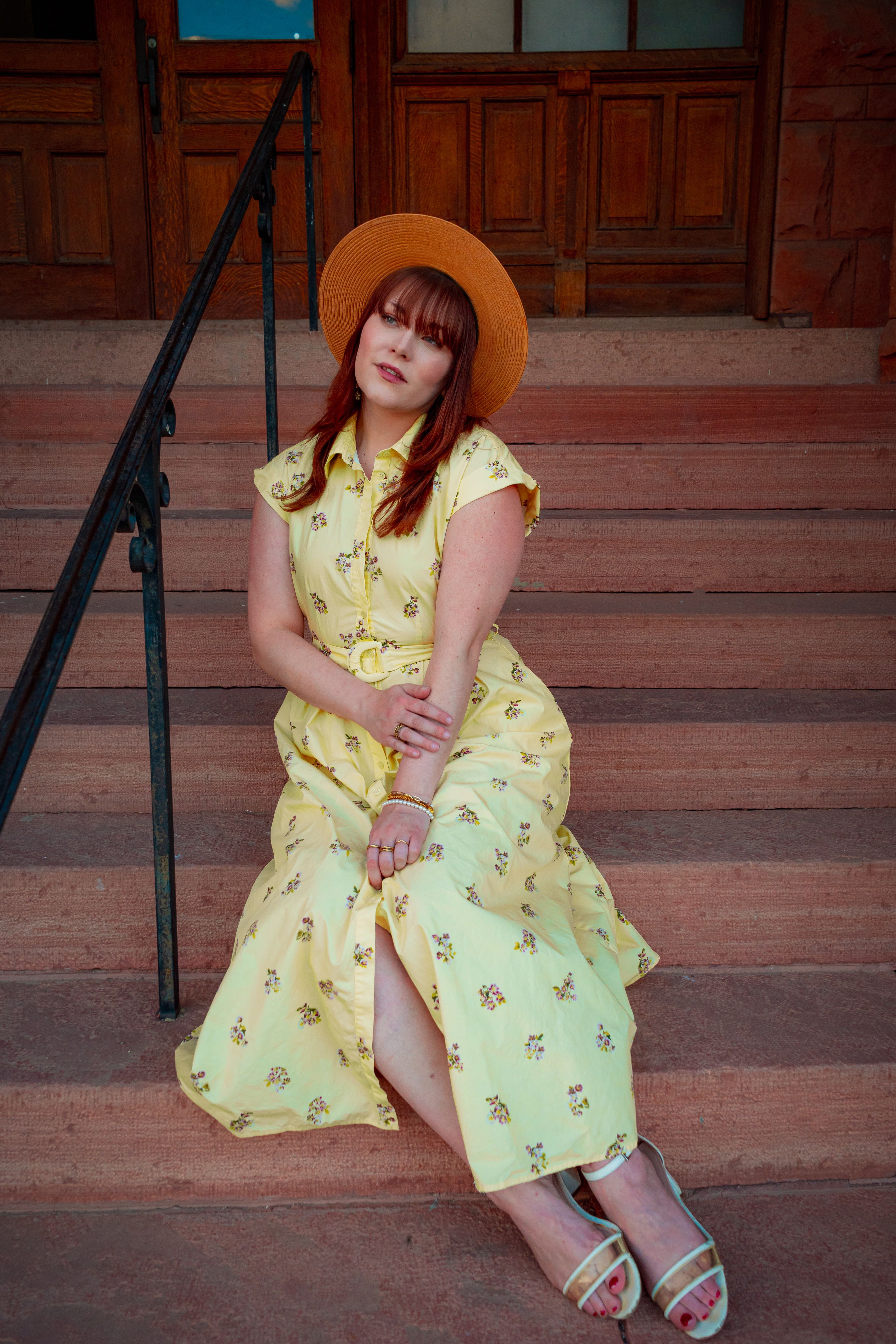 Chic portrait of a woman in a yellow dress and straw hat, set on outdoor stairs in Westminster, Colorado.
