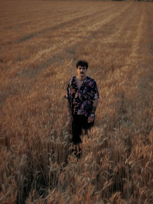 Free A man stands in a golden wheat field, capturing the essence of rural tranquility and nature's beauty at sunset. Stock Photo