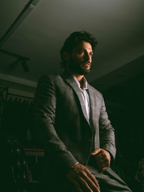 Free Man in a gray suit sitting indoors under dramatic lighting. Captivating and stylish. Stock Photo