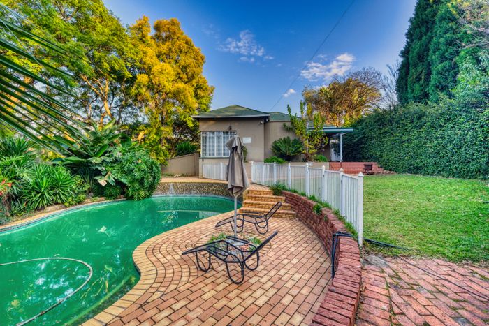 Brick patio with pool surrounded by a landscaped garden