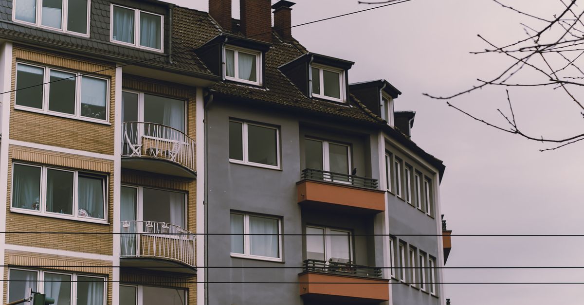 European-style residential building exterior with balconies, under an overcast sky.