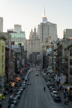 A lively city street scene in Manhattan with skyscrapers and busy traffic at dusk.