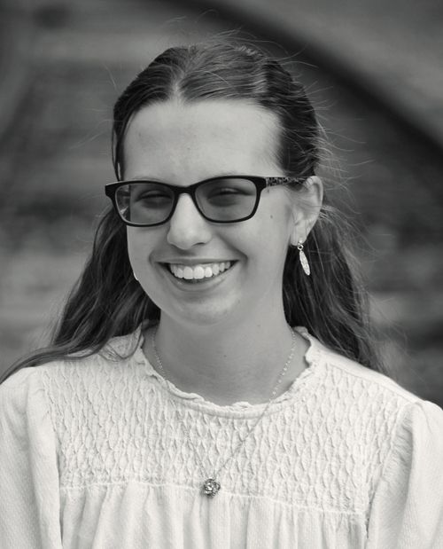 Free A cheerful young woman wearing glasses in a black and white portrait outdoors. Stock Photo