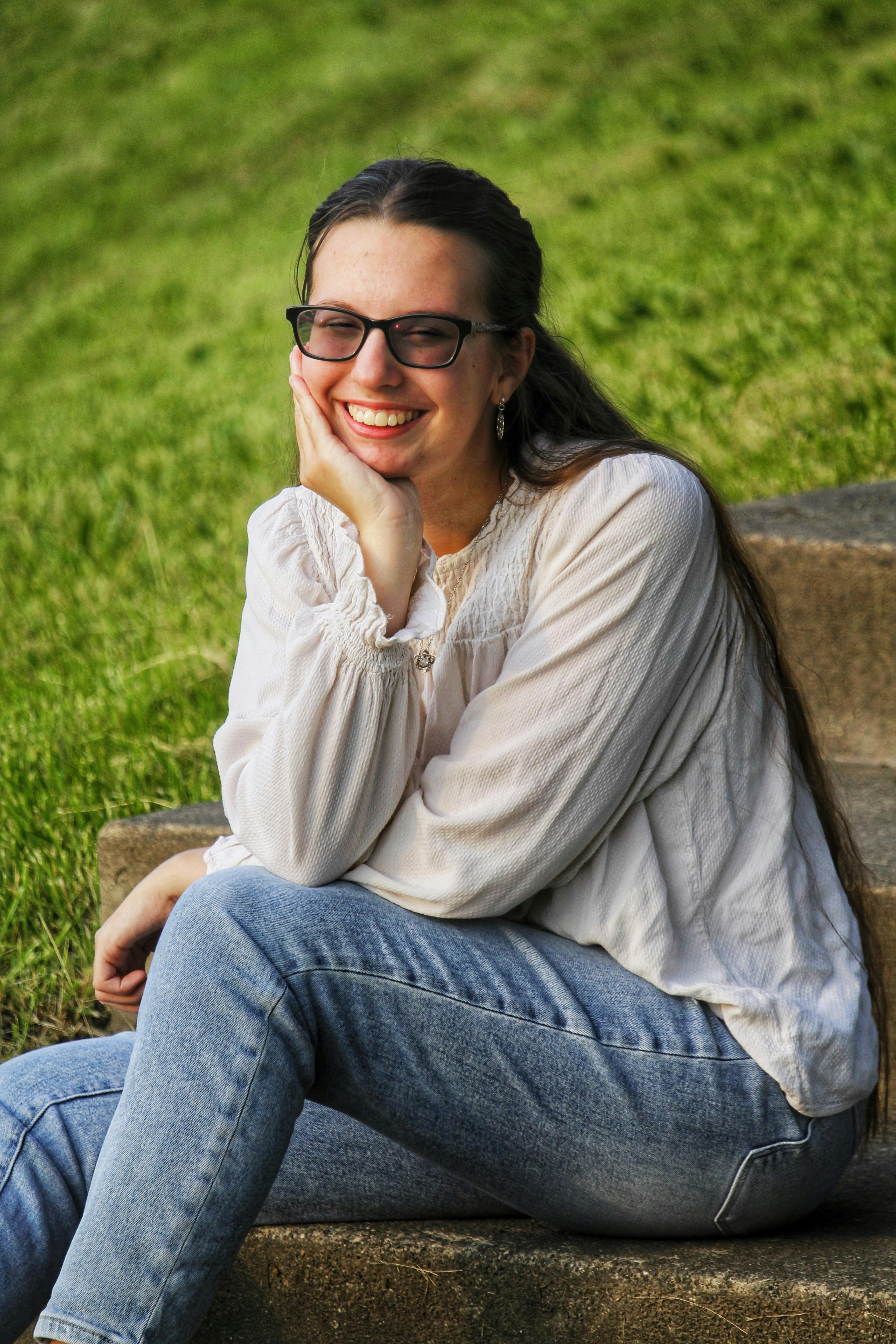 Smiling young woman sitting on outdoor steps, enjoying a bright day.