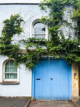 Quaint English mews featuring a blue door and lush greenery in a picturesque setting.