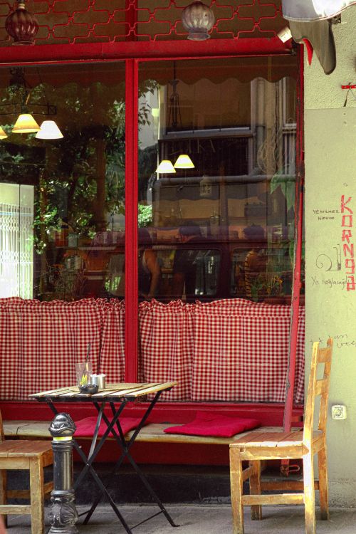 Free Cozy outdoor cafe with red checkered curtains and wooden chairs. Stock Photo