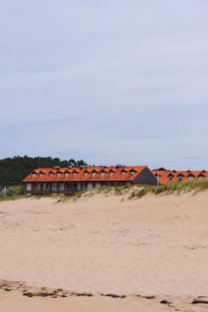 Coastal houses with red roofs along the sandy beach of Somo, Spain.