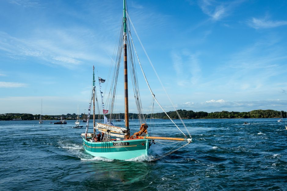 Traditional sailboat navigating Brittany's picturesque waters under a clear blue sky.