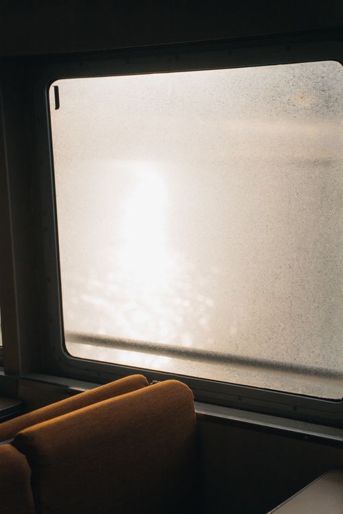Free Misty sunlight streaming through a ferry window with reflections on the water, creating a peaceful atmosphere. Stock Photo