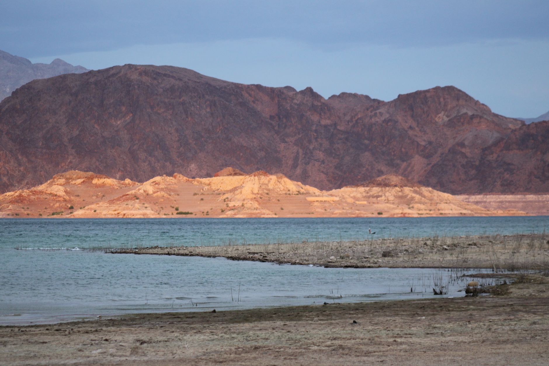 Blue water of Lake Mead ringed by pale bathtub rings of desert cliff
