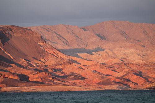 Free A breathtaking view of the rugged red rock mountains by Lake Mead at sunset. Stock Photo