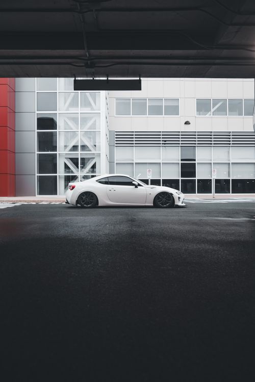 Free Modern white sports car parked outside a contemporary building, showcasing style and design. Stock Photo
