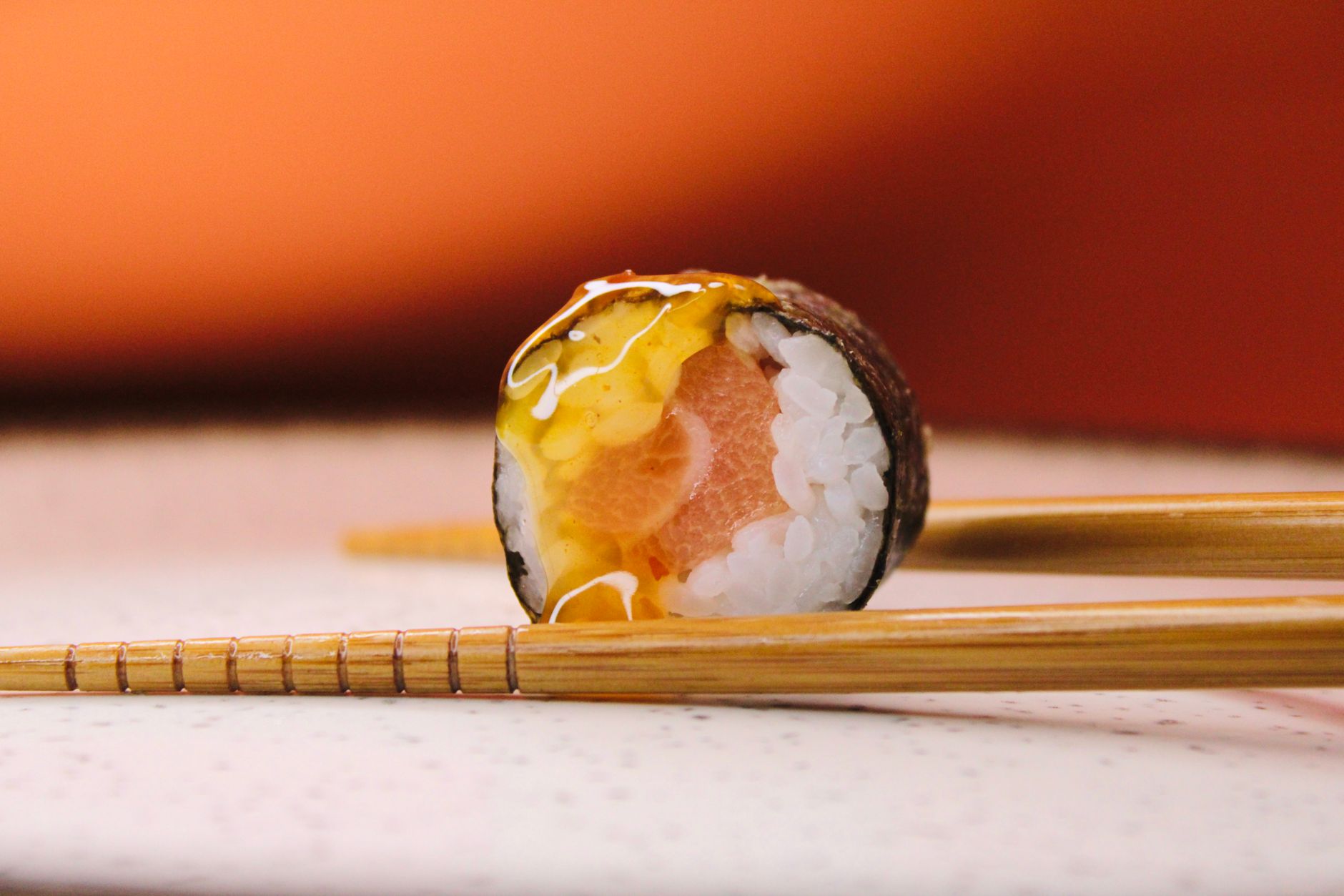 Close-up of a slice of smoked pink salmon sushi with pickled ginger