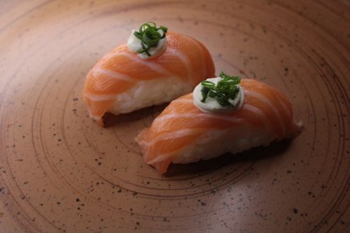Free Delicious salmon nigiri sushi garnished with green onions on a ceramic plate. Stock Photo