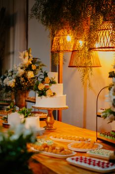 A beautifully decorated wedding cake table with floral arrangements and elegant lighting, creating a warm ambiance.