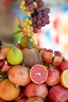 A colorful display of tropical and citrus fruits, including grapes, pomegranates, and grapefruit.