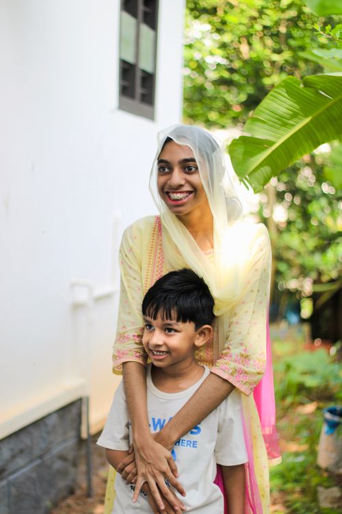 Free A cheerful mother in a headscarf embraces her son in a lush garden setting, exuding warmth and happiness. Stock Photo