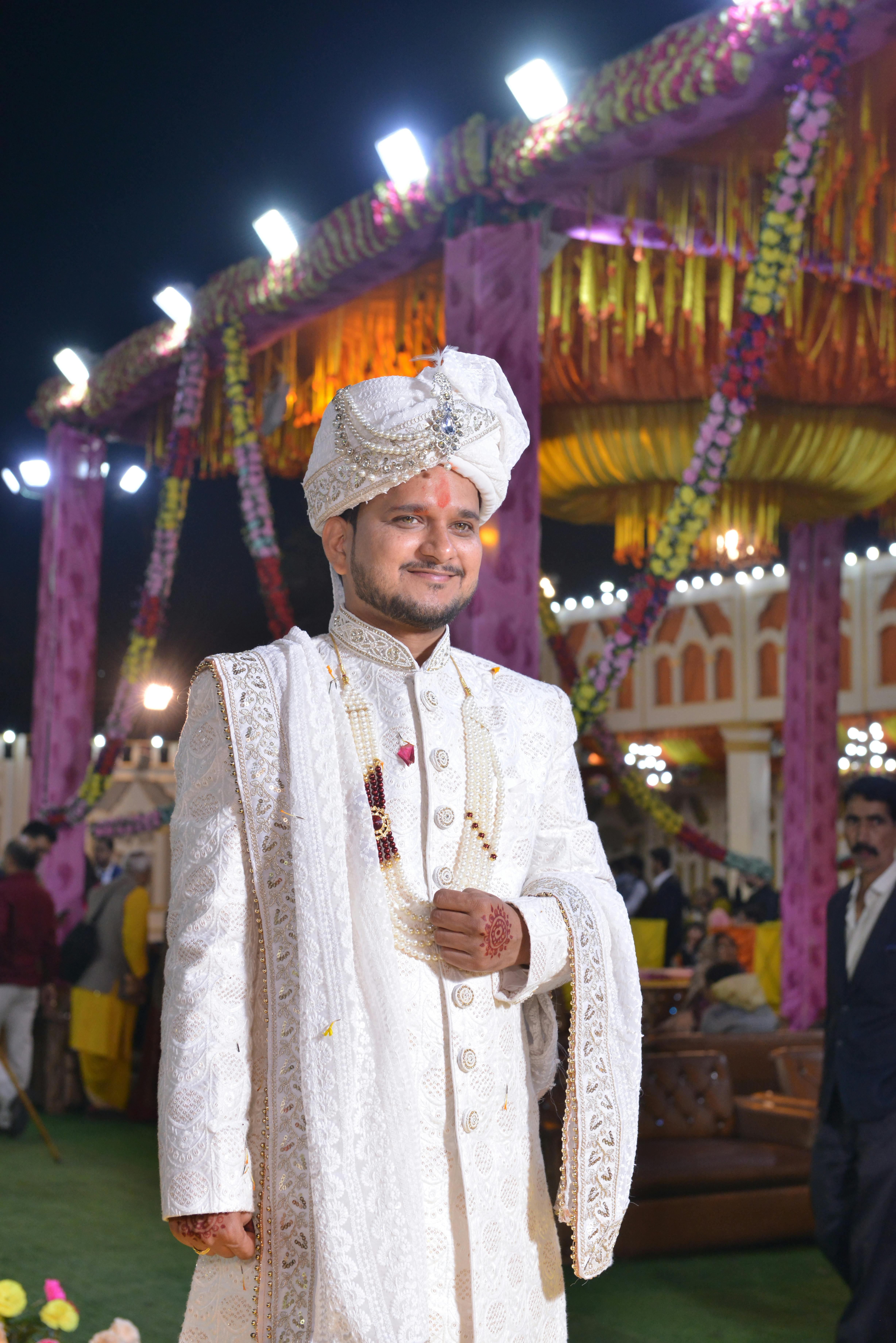 Elegant groom in traditional attire at night Indian wedding ceremony.